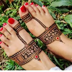 two feet with henna tattoos and red nail polishes on their toenails