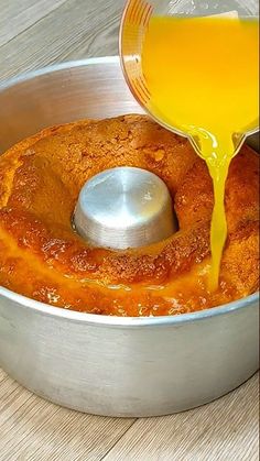 someone pouring orange juice into a metal pan