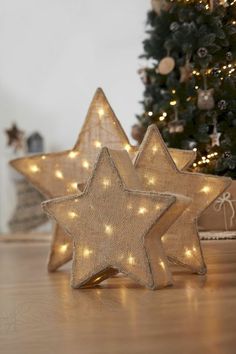 two star shaped lights sitting on top of a wooden table next to a christmas tree