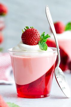 a dessert with strawberries and whipped cream in a small glass on a white table