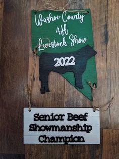 a sign hanging from the side of a wooden wall that says, warrior county livestock show