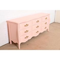 a pink dresser with gold handles and drawers