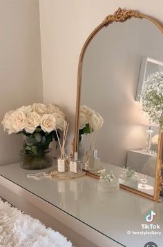 there is a mirror and flowers on the dresser