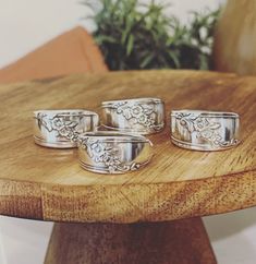 three silver dishes sitting on top of a wooden table next to a potted plant