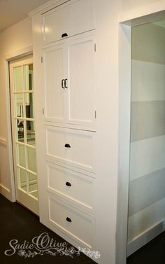 an empty room with white cabinets and glass doors on the wall, in front of a closet