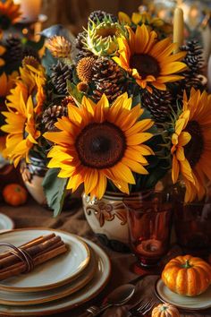 sunflowers and pine cones are arranged in a vase on a table with candles