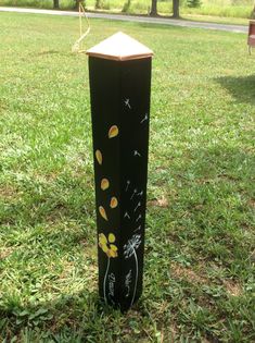 a black box with yellow flowers painted on it in the middle of a grassy field