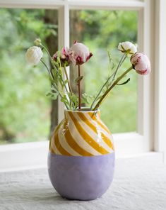 a vase filled with flowers sitting on top of a window sill next to a window