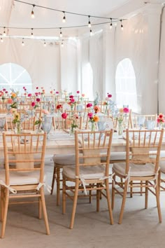 the tables and chairs are set up for an event with floral centerpieces on them