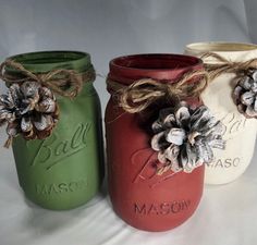 three mason jars with pine cones on them