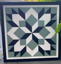 a blue and white quilt sitting on top of a wooden table next to a potted plant