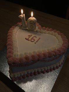 a heart shaped cake with two candles on it and the number sixteen in the shape of a heart