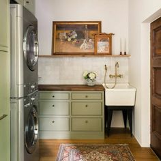 a washer and dryer in a small room next to a doorway with a painting on the wall