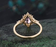 a gold ring with a pink stone in the center on top of a green rock