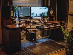 a computer desk with two monitors and keyboards on it, in front of a window