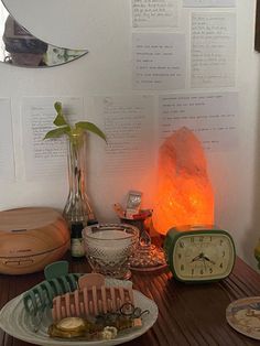 a table topped with plates filled with food next to a clock and other items on top of a wooden table