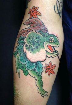 a frog tattoo on the arm with flowers