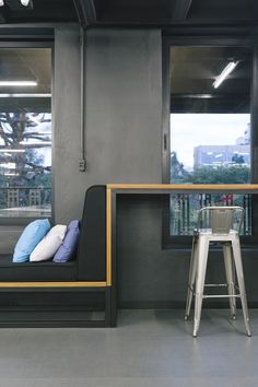 a chair and table in a room with large windows on both sides, next to a window seat