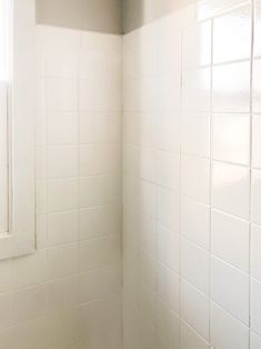 the corner of a bathroom with white tiles