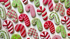 many decorated cookies are displayed on a white surface with candy canes and candies