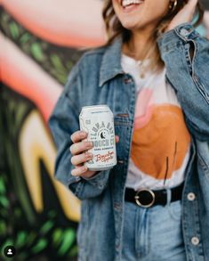 a woman holding a can of beer in her hands