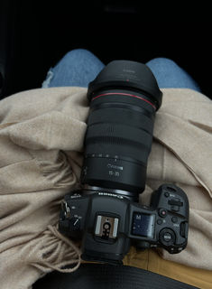 a camera sitting on top of a blanket next to a person's feet and legs