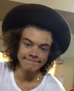 a young man wearing a black hat and white t - shirt smiling at the camera