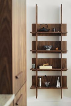 a wooden shelf filled with lots of items next to a wall mounted cabinet in a room