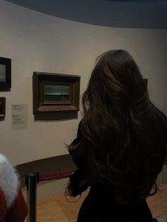 a woman looking at paintings on display in a museum