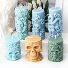 the candles are decorated with skulls and flowers in pastel blue, green, yellow and orange