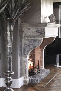 a large vase filled with flowers next to a fire place