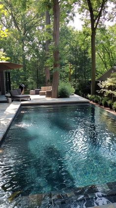 an outdoor swimming pool with lounge chairs and trees in the backgroung area