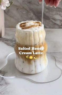 someone is pouring honey into a cream latte in a jar with the words salted honey cream latte on it