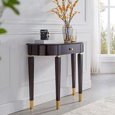 a black and gold console table next to a white wall with flowers in vases