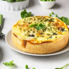 a quiche on a white plate with green vegetables