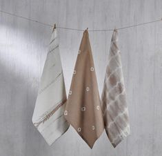 three towels hanging from a clothes line on a string in front of a white wall