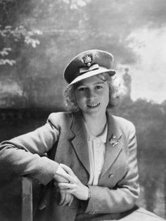 an old black and white photo of a woman wearing a hat sitting on a bench