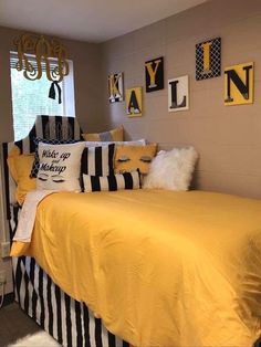 a bedroom with yellow and black bedding, striped comforter, and pictures on the wall