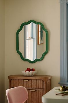 a mirror on the wall above a dresser with a bowl of fruit in front of it