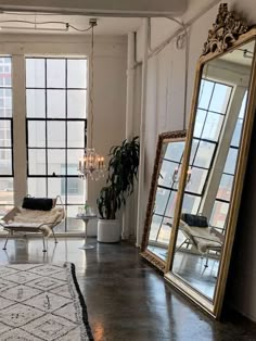 a living room filled with lots of windows and furniture next to large mirrors on the wall