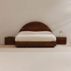 a bed sitting on top of a white floor next to a wooden headboard and night stand