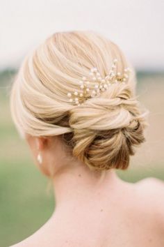 a woman with blonde hair wearing a bridal hairstyle and pearls in her hair