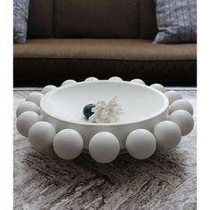 a white bowl sitting on top of a table next to a brown couch and pillows