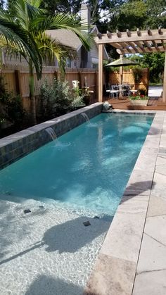 an empty swimming pool in the middle of a backyard with a pergolated patio