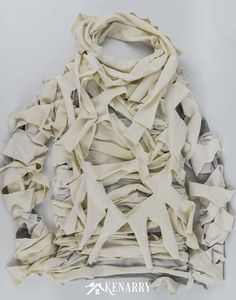 a white scarf with many pieces of fabric on it