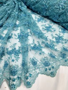 This beautiful beaded lace fabric is perfect for creating stunning apparel and accessories. The turquoise color and floral pattern make it ideal for weddings, special occasions, and even dance or sportswear. The fabric is made of high-quality synthetic fiber and is embroidered with sequins, beads, and rhinestones, adding a touch of glamour to any project. Sold by the yard, this handmade fabric is 46'' to 60'' in width and is suitable for apparel such as dresses, loungewear, and saris, as well as accessories like bags, purses, hats, and costumes. It is medium in weight and comes from Korea, Republic of. Create your next project with this beautiful beaded embroidery bridal lace fabric. Fitted Bollywood Style Embroidered Lace Fabric, Festive Fitted Sequin Fabric With Lace Work, Festive Fitted Lace Fabric, Traditional Lace Dupatta With Sequins, Blue Lace Dupatta For Wedding, Blue Lace Wedding Dupatta, Festive Lace Dupatta With Sequins, Fitted Beaded Lace Embroidered Fabric, Bollywood Style Embroidered Lace Fabric