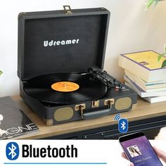 a record player sitting on top of a table next to a cell phone and books