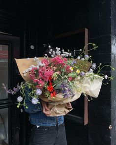 a person holding a bouquet of flowers in front of a door with a black background