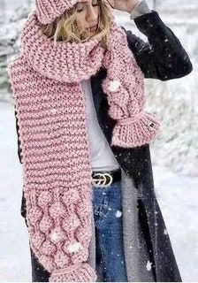 a woman is standing in the snow wearing a pink knitted scarf and matching hat