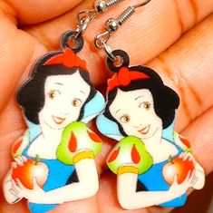 a pair of snow white and the seven dwarfs dangles are being held by someone's hand